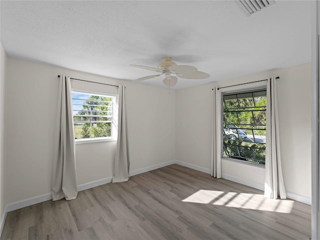 empty room with ceiling fan, light hardwood / wood-style flooring, and a textured ceiling