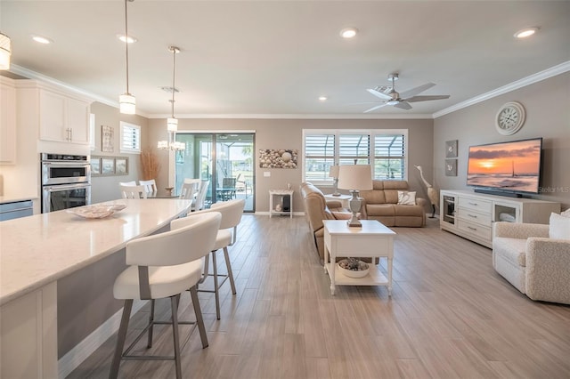 kitchen with a breakfast bar, decorative light fixtures, light wood-type flooring, stainless steel double oven, and light stone countertops