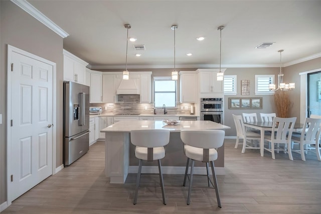 kitchen featuring stainless steel appliances, white cabinetry, a center island, and sink