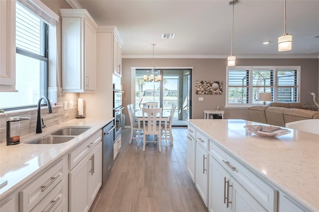 kitchen with sink, dishwasher, white cabinetry, light stone countertops, and decorative light fixtures