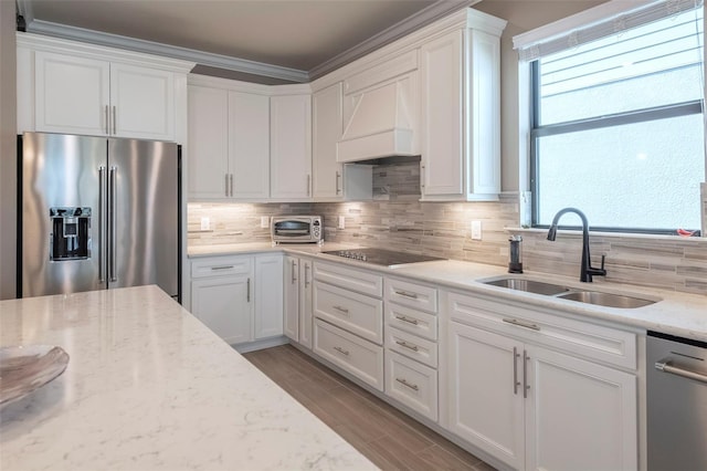 kitchen featuring sink, appliances with stainless steel finishes, white cabinetry, light stone countertops, and custom range hood