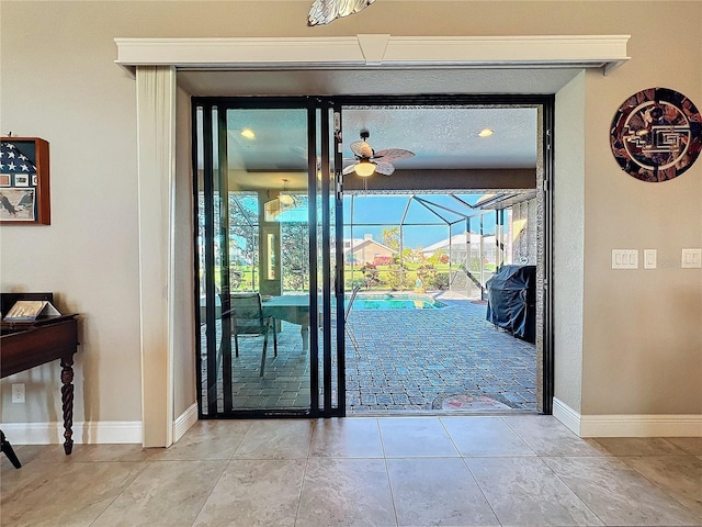 doorway with light tile patterned floors and ceiling fan