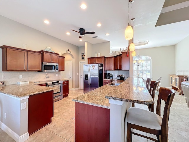 kitchen with sink, a kitchen breakfast bar, kitchen peninsula, pendant lighting, and stainless steel appliances