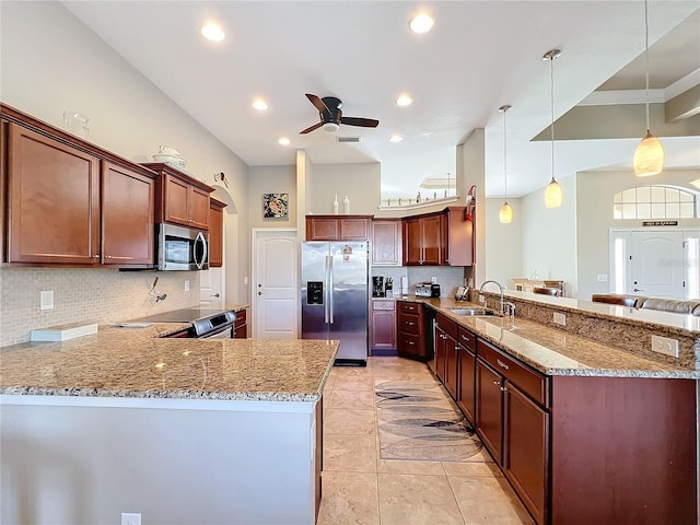 kitchen with sink, kitchen peninsula, pendant lighting, stainless steel appliances, and light stone countertops