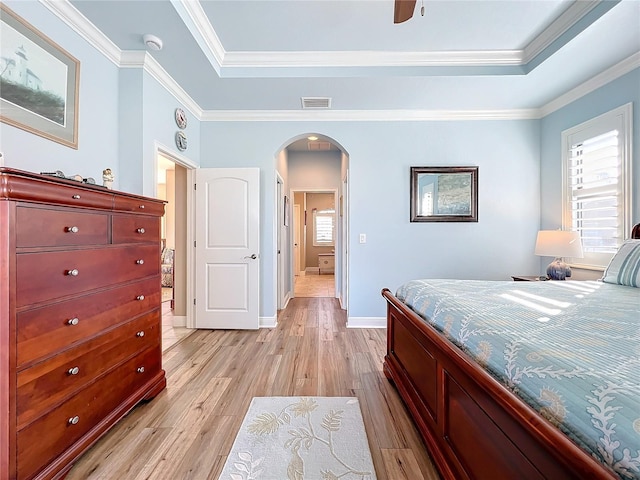 bedroom featuring a raised ceiling, crown molding, ceiling fan, and light hardwood / wood-style flooring