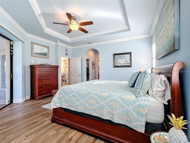 bedroom with crown molding, light hardwood / wood-style flooring, a raised ceiling, and ceiling fan