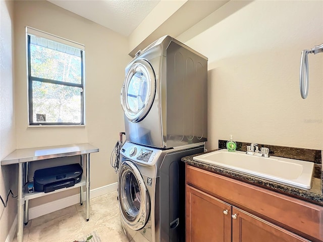 washroom featuring cabinets, stacked washer and clothes dryer, sink, and a textured ceiling