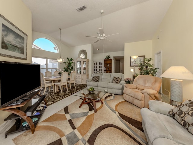 living room with ceiling fan with notable chandelier and high vaulted ceiling