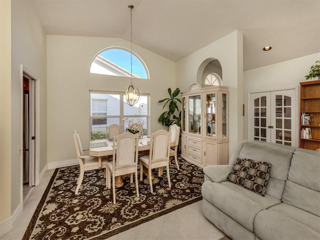 dining space with light tile patterned floors, vaulted ceiling, french doors, and a chandelier