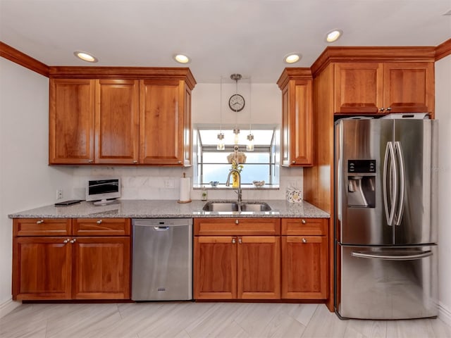 kitchen featuring light stone countertops, appliances with stainless steel finishes, sink, and pendant lighting