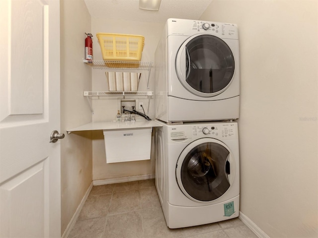 clothes washing area with stacked washer / drying machine and light tile patterned floors