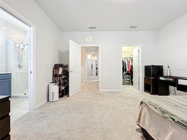 carpeted bedroom featuring a walk in closet, ensuite bath, and a closet