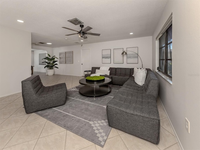 tiled living room with ceiling fan and a textured ceiling