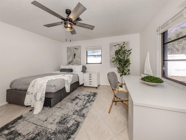 bedroom featuring ceiling fan, light tile patterned floors, and a textured ceiling