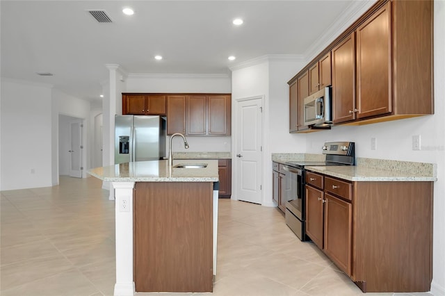 kitchen with sink, appliances with stainless steel finishes, light stone counters, ornamental molding, and a center island with sink