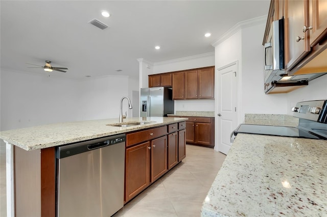 kitchen with sink, stainless steel appliances, light stone counters, ornamental molding, and a center island with sink