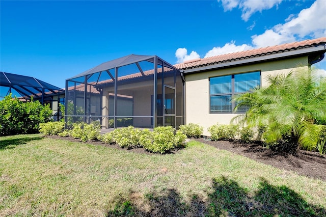 back of property featuring a lanai and a lawn