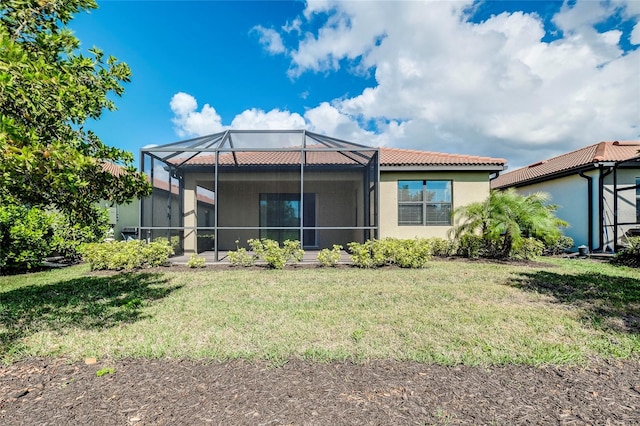 rear view of property with glass enclosure and a lawn