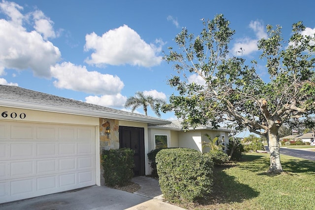 ranch-style house featuring a garage, a front yard, concrete driveway, and stucco siding