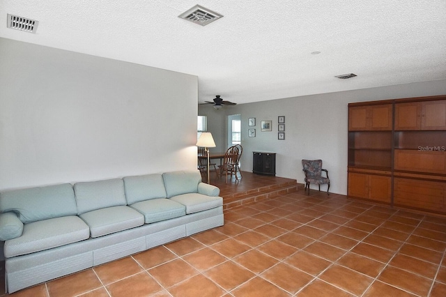 tiled living room featuring ceiling fan and a textured ceiling