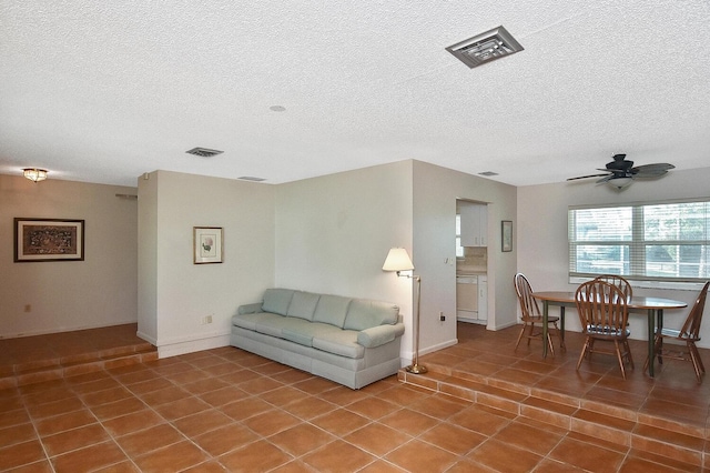 living room with ceiling fan, tile patterned floors, and a textured ceiling