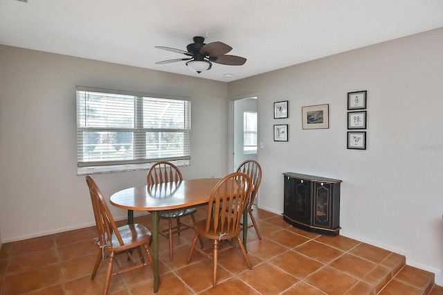 tiled dining area featuring ceiling fan and baseboards