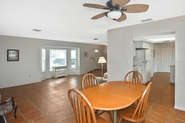 dining area featuring tile patterned flooring, ceiling fan, and a textured ceiling