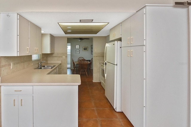 kitchen featuring light countertops, backsplash, freestanding refrigerator, a sink, and tile patterned flooring