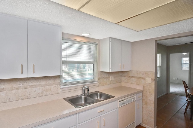 kitchen featuring dark tile patterned flooring, a sink, white cabinetry, light countertops, and dishwasher