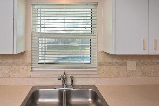 details with light countertops, white cabinetry, a sink, and decorative backsplash