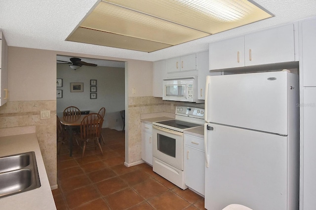 kitchen with sink, white appliances, ceiling fan, white cabinets, and dark tile patterned flooring