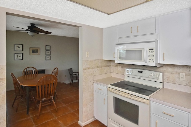 kitchen featuring white cabinetry, white appliances, dark tile patterned flooring, and a textured ceiling