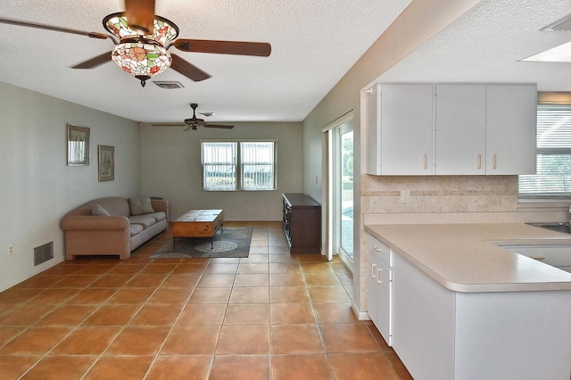 unfurnished living room with sink, a healthy amount of sunlight, light tile patterned floors, and a textured ceiling