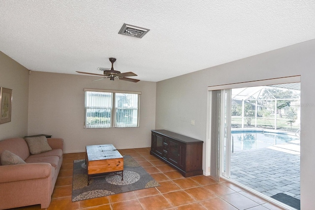 living room with a textured ceiling, plenty of natural light, tile patterned floors, and ceiling fan