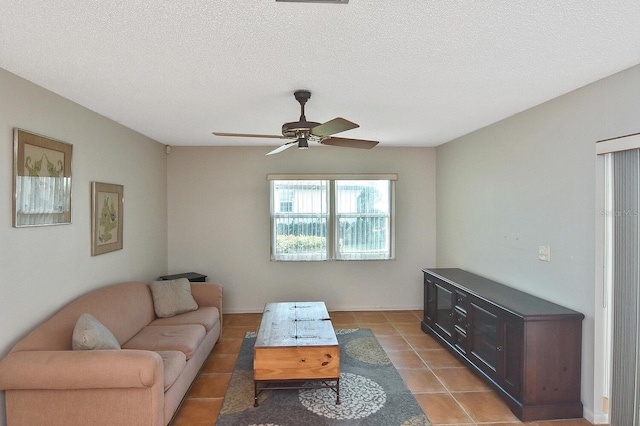 living room with a ceiling fan, a textured ceiling, and light tile patterned floors