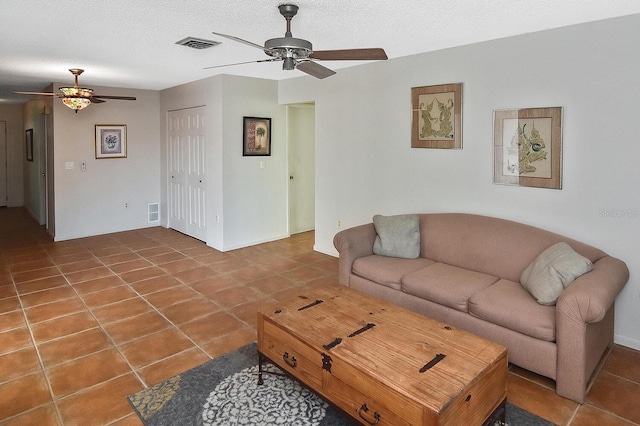 living room featuring tile patterned flooring, ceiling fan, and a textured ceiling