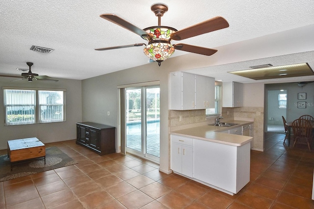 kitchen with sink, white cabinetry, decorative backsplash, tile patterned floors, and kitchen peninsula