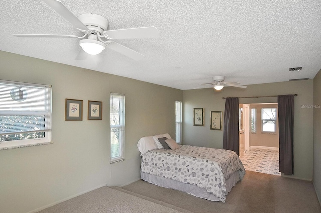 carpeted bedroom featuring a textured ceiling, visible vents, and a ceiling fan