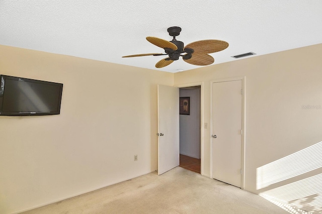 carpeted empty room with ceiling fan and a textured ceiling