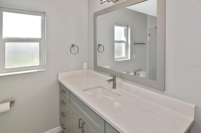 bathroom featuring toilet, baseboards, and vanity