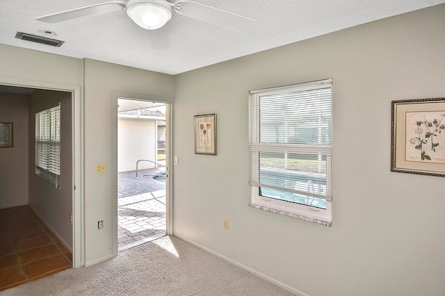 doorway featuring ceiling fan, light colored carpet, and a textured ceiling