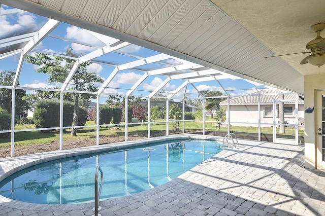 view of pool featuring ceiling fan, a lawn, glass enclosure, and a patio area