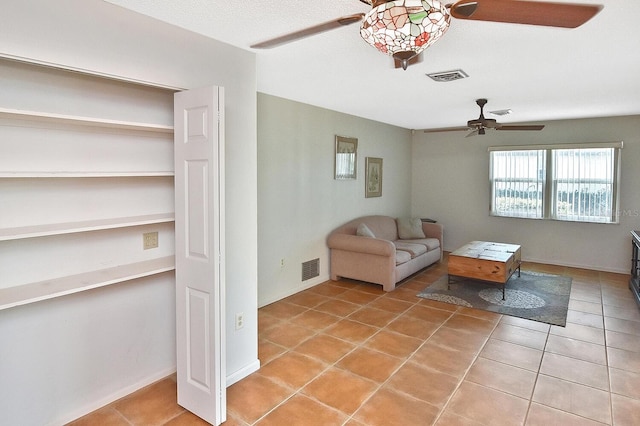 unfurnished living room featuring baseboards, light tile patterned flooring, visible vents, and a ceiling fan