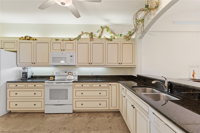 kitchen featuring sink, white appliances, ceiling fan, cream cabinetry, and dark stone counters