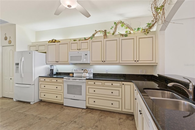 kitchen with sink, dark stone counters, ceiling fan, white appliances, and cream cabinetry