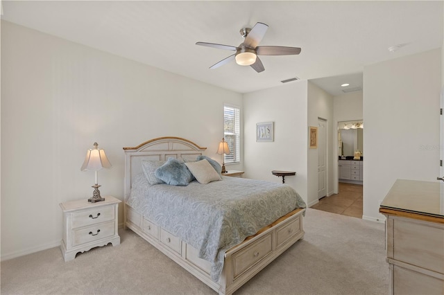 bedroom with light carpet, ensuite bath, and ceiling fan