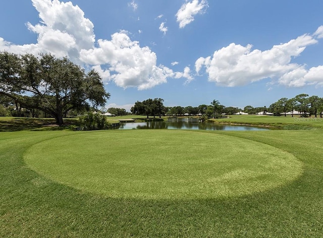 view of home's community with a water view, a lawn, and golf course view