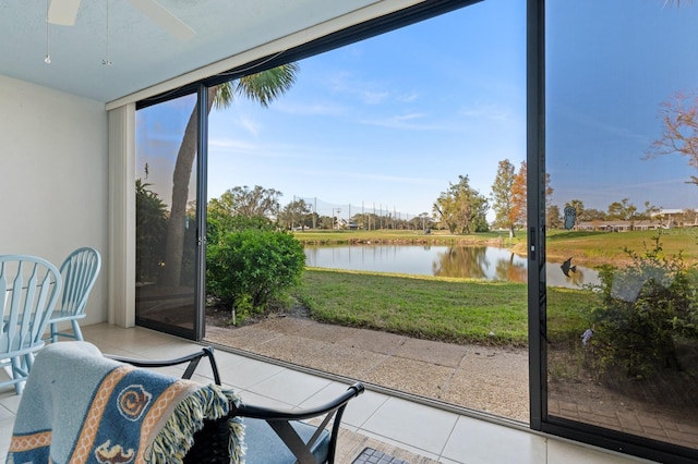 sunroom featuring ceiling fan and a water view