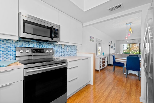 kitchen featuring white cabinetry, hanging light fixtures, light hardwood / wood-style flooring, and stainless steel appliances