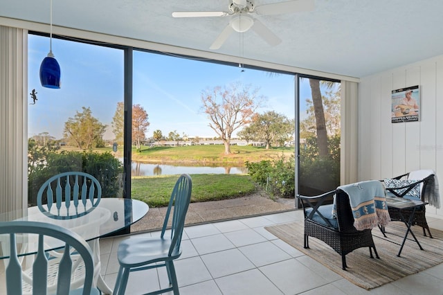 sunroom with a water view and ceiling fan